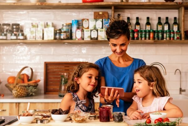 Little sisters cooking with her mother in the kitchen.